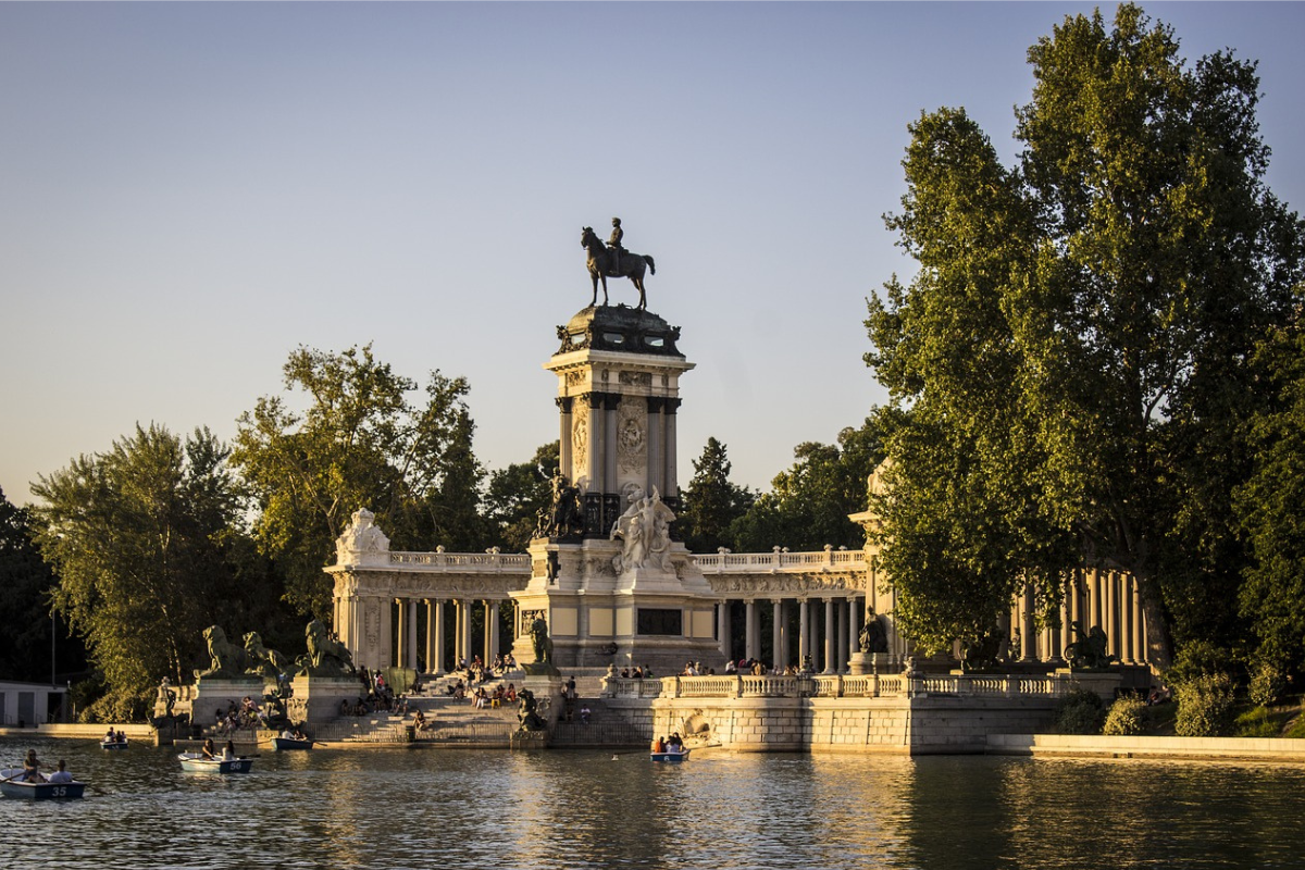 There is a statue on top and water in surrounding and people are enjoying boat tour 