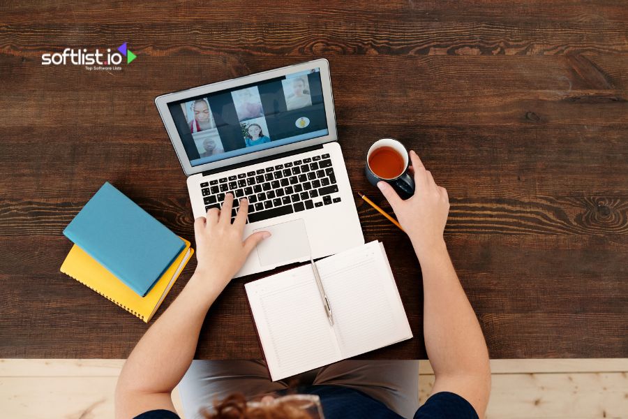 Person using a laptop with video conferencing, notebook and coffee on the desk