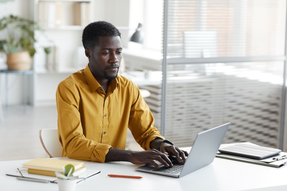Leave request workflow: employee wearing a yellow, long sleeved polo, using a laptop