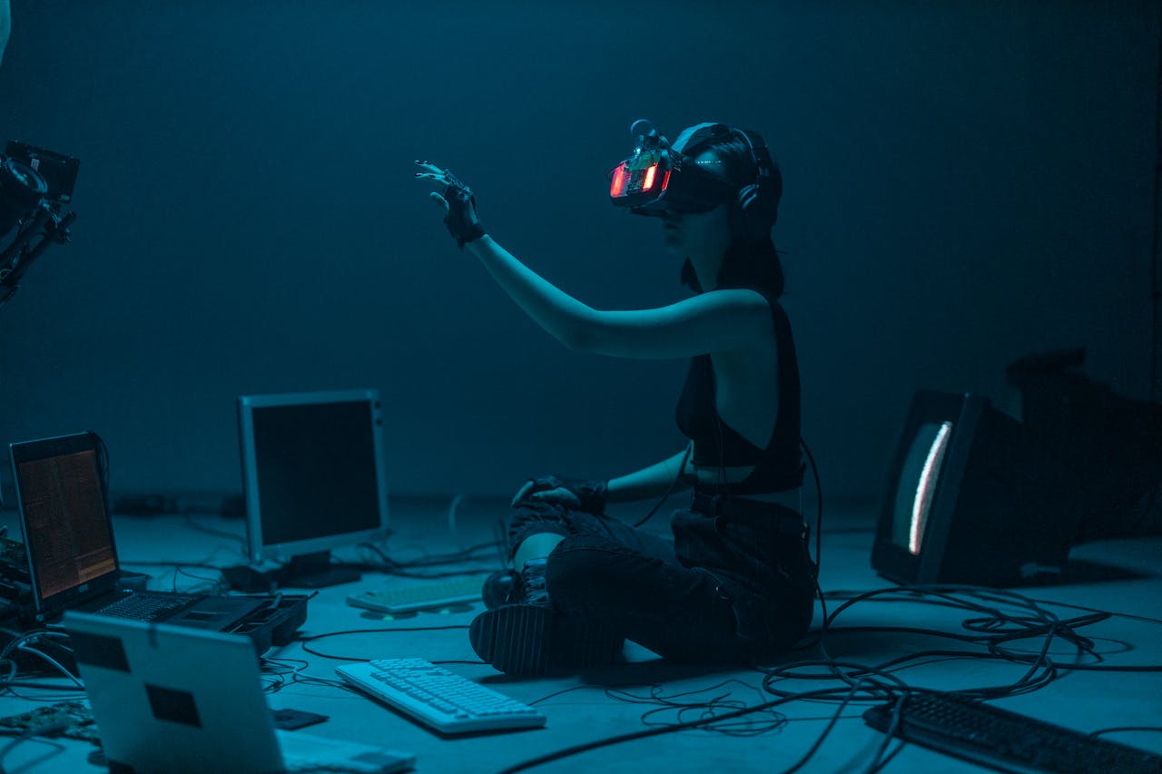 A woman with a headset and a VR Glasses infront of various computer