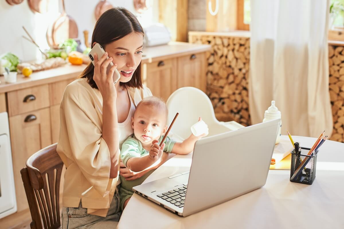 Mother taking care of her baby while talking on the phone and working from home