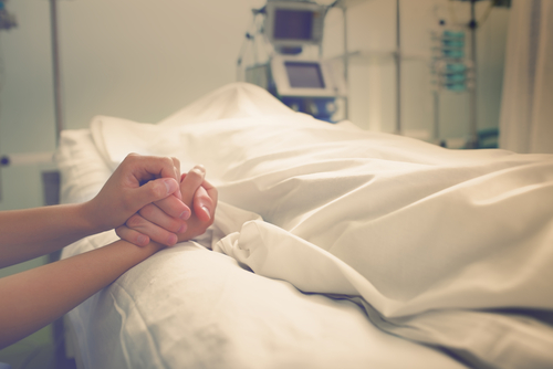 A family holding the hands of a loved one who was lost due to wrongful death in a hospital 