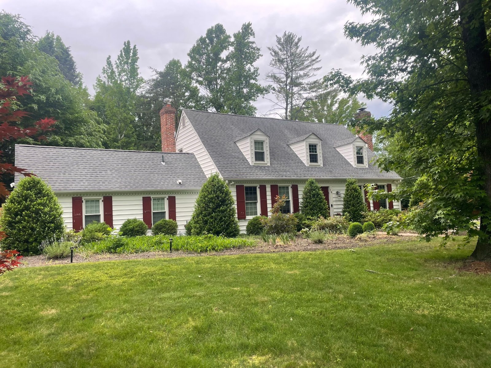 Comparison of new and old roofs.Colonial-style home in Cherry Hill with a newly installed gray shingle roof, demonstrating the outcome of choosing roof replacement over repair for enhanced curb appeal.