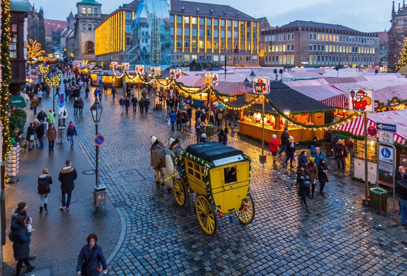 A street with people and a carriage

Description automatically generated