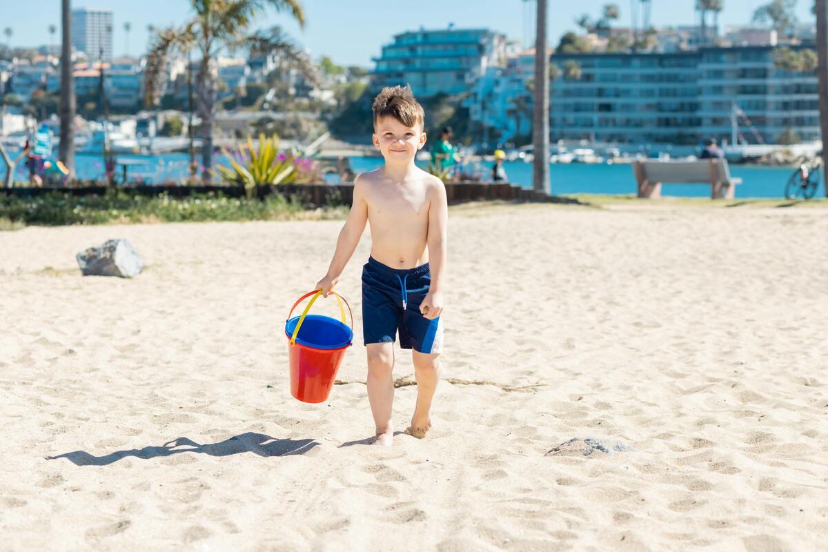 A kid with a bucket on the beach

