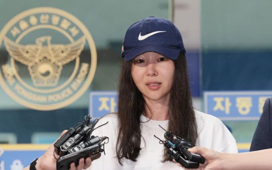 This contain an image ofMin Hee Jin holding two gloves in front of a man wearing a baseball cap and uniform