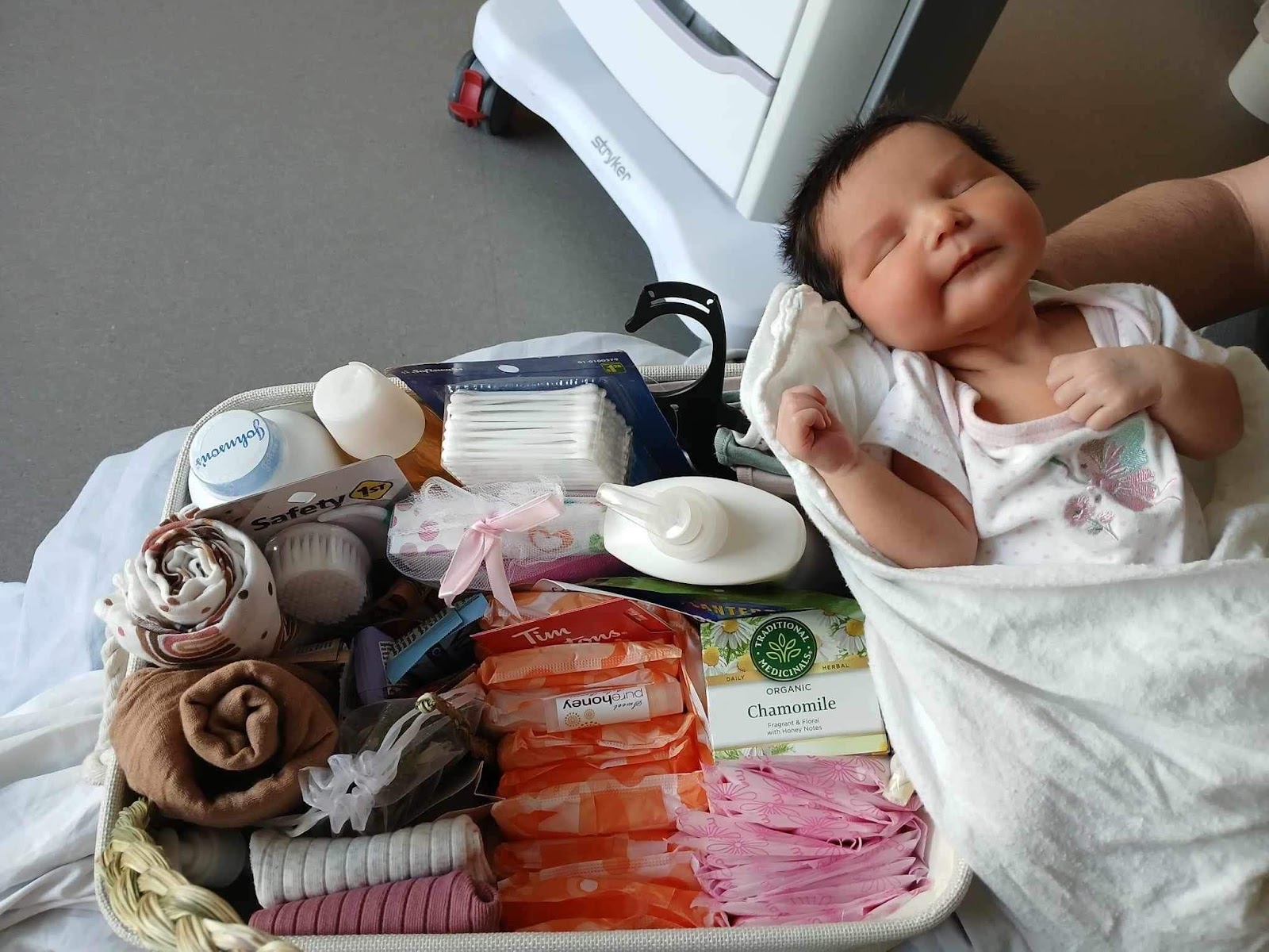 A newborn next to one of Blue Feather’s baby welcoming baskets.