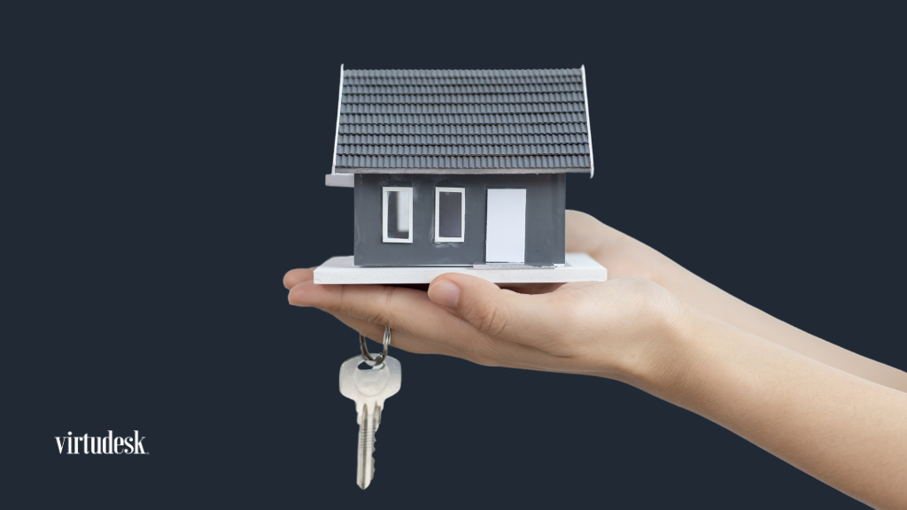 A person holds a small house model in one hand while displaying keys in the other, symbolizing home ownership.