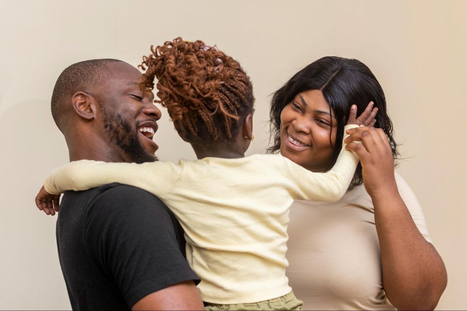 Joyful family moment showing parents and child in a warm embrace, illustrating the emotional benefits of effective co-parenting boundaries and family unity.