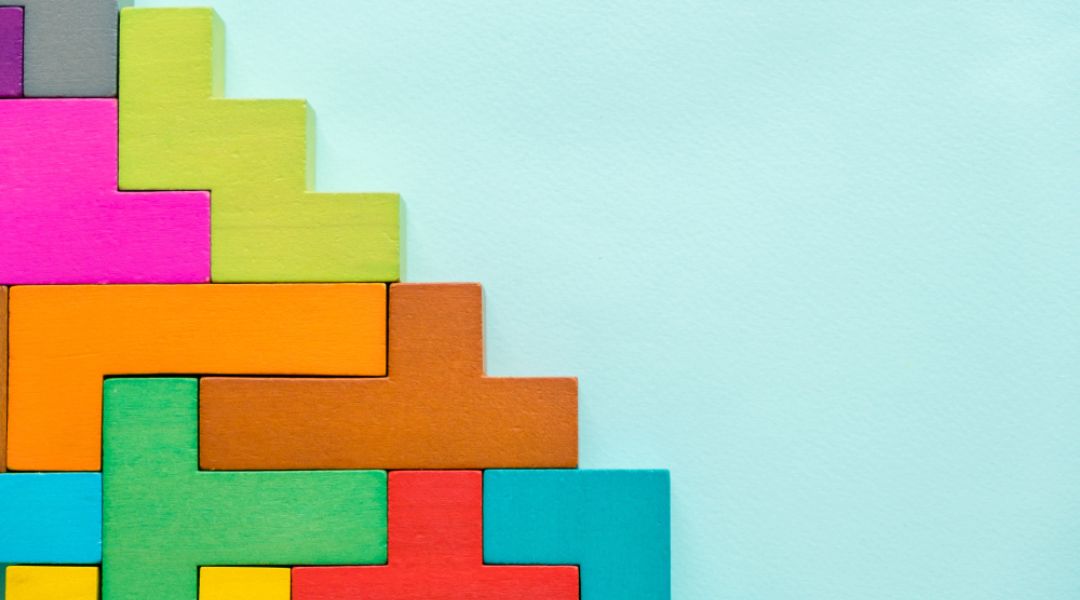Colorful interlocking wooden blocks arranged in a corner pattern on a light blue background. 