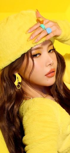 This contains an image of MAMAMOO Solar's with long hair wearing a yellow outfit and holding her hands up to her head