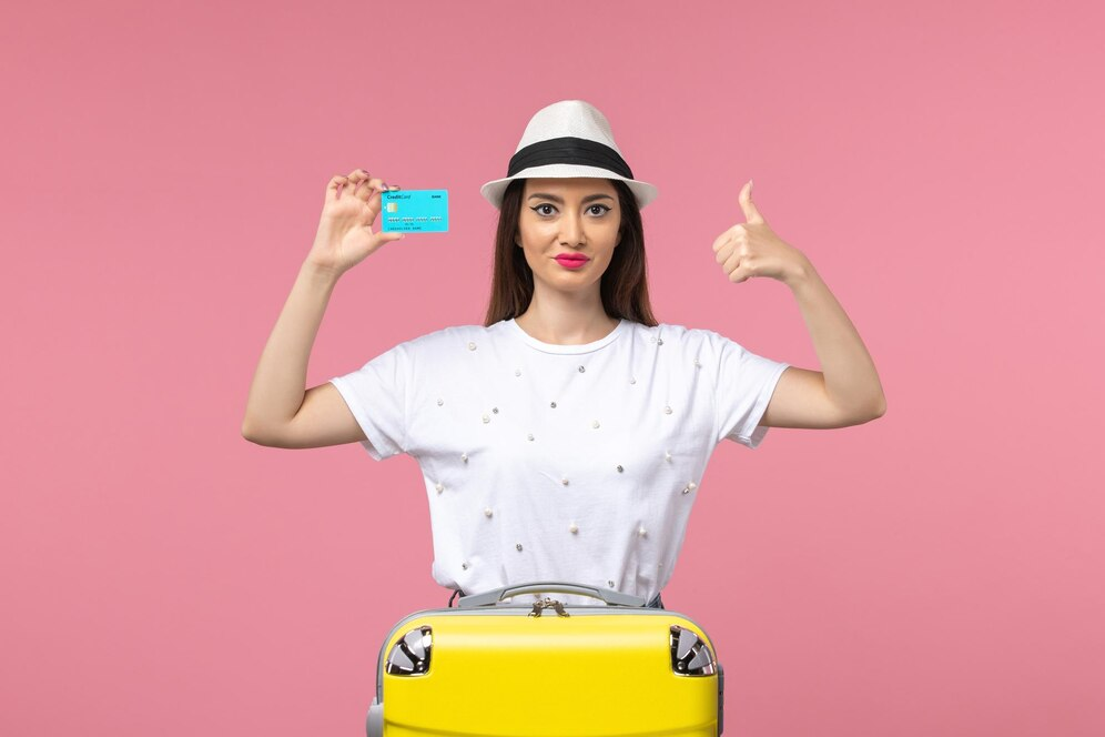 A person holding up a card and a yellow suitcaseDescription automatically generated