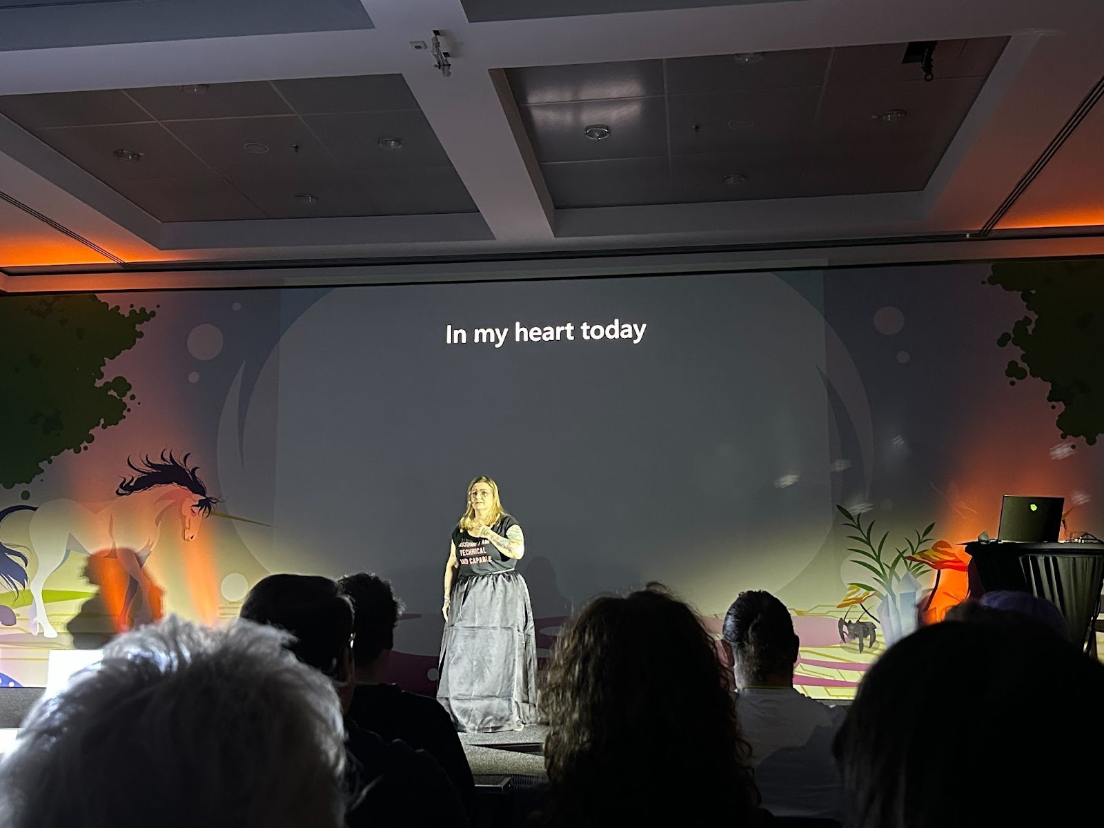 Picture of a woman standing alone on a stage. The text "In my heart today" is visible behind her