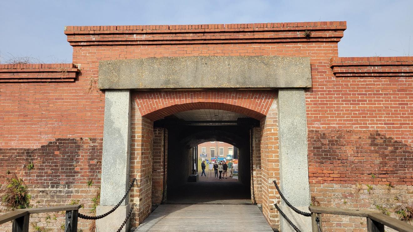 A brick archway with people walking in the background

Description automatically generated