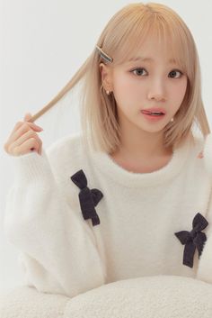 A picture of LE SSERAFIM's Chaewon wearing a off-white sweater with her hand on her head 