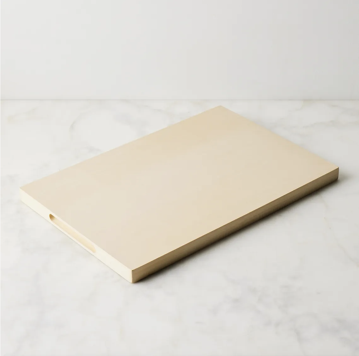 Cream-colored rubber cutting board on a marble countertop.