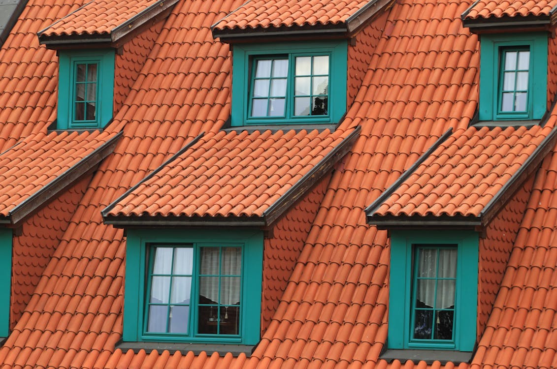 Close-up view of a green house with a clean, vibrant orange roof, highlighting well-maintained exterior surfaces.