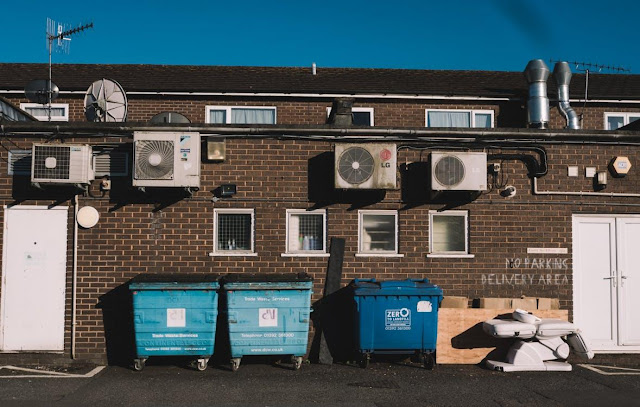 Free Industrial Bins near the Brown Brick Wall Stock Photo