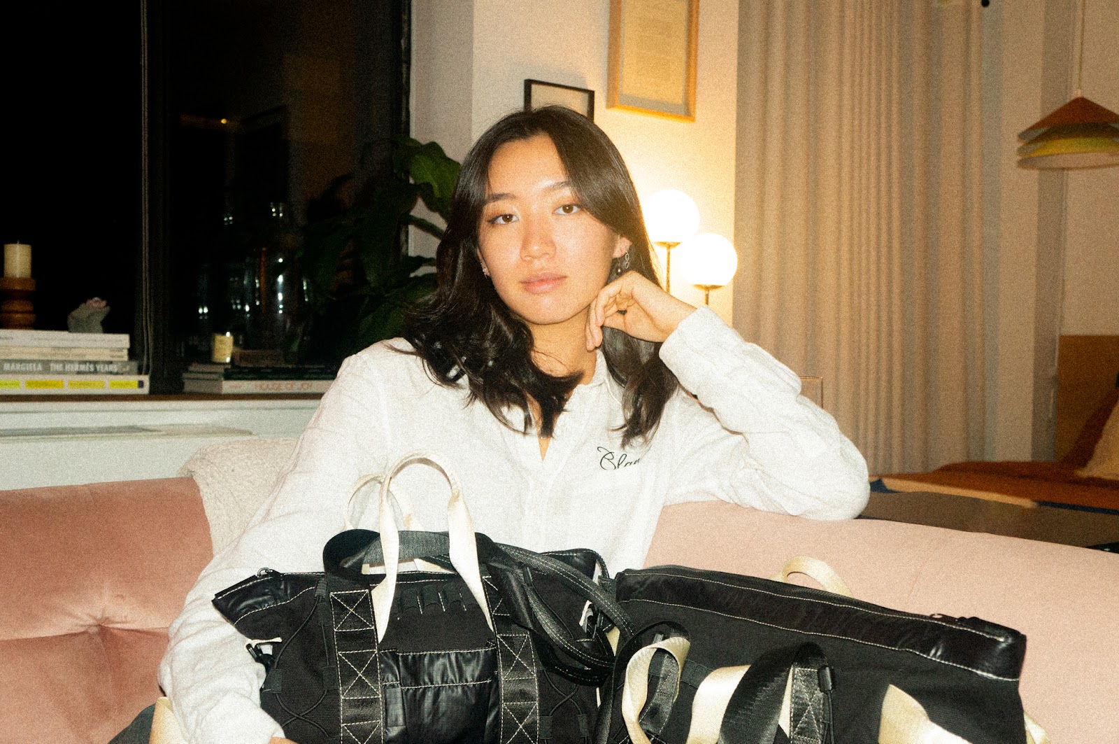 Flora Hu sitting on a couch with two FHD Utility Totes displayed in front of her. 