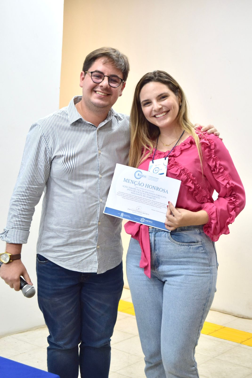 Pessoas posando para foto segurando placaDescrição gerada automaticamente