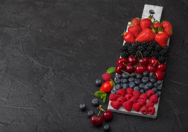 An assortment of fresh berries arranged on a marble board