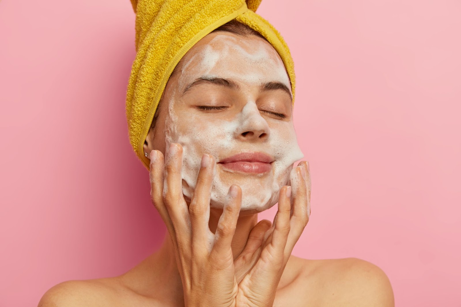 Woman washing her face with cleanser, showing gentle skincare routine for oily skin.

