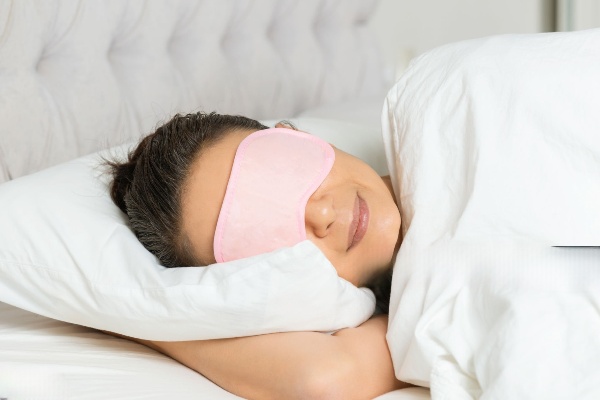 A woman sleeping soundly on her side with an anti-snore pillow between her head and shoulders.