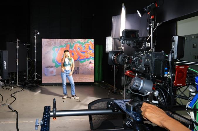 A person in a studio with a video camera

Description automatically generated