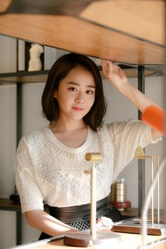 This contains an image of Moon Geun-young standing in front of a wooden shelf