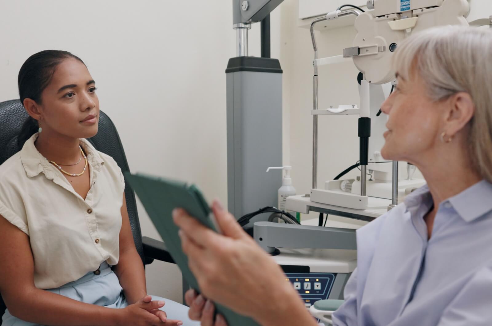 An eye doctor holding a tablet in her hands going over eye exam results with a female patient.