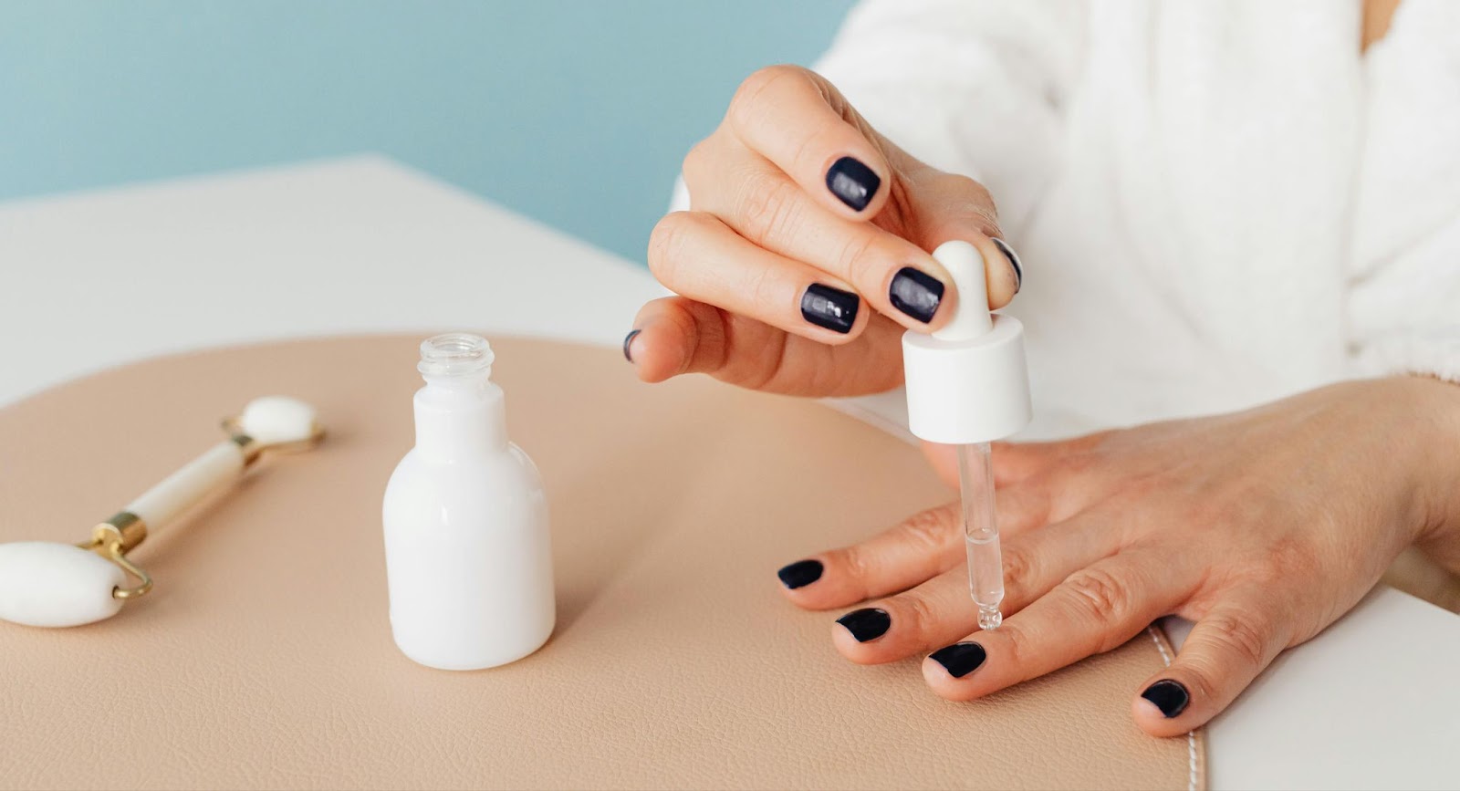 Person applies cuticle oil from a dropper to the base of fingernails for nail growth