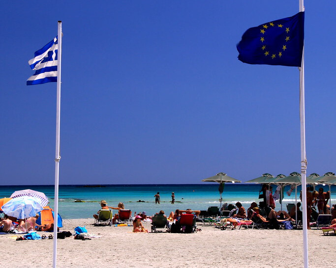 People enjoying a picnic on the pink sands of Elafonisi Beach with the blue water in the background.