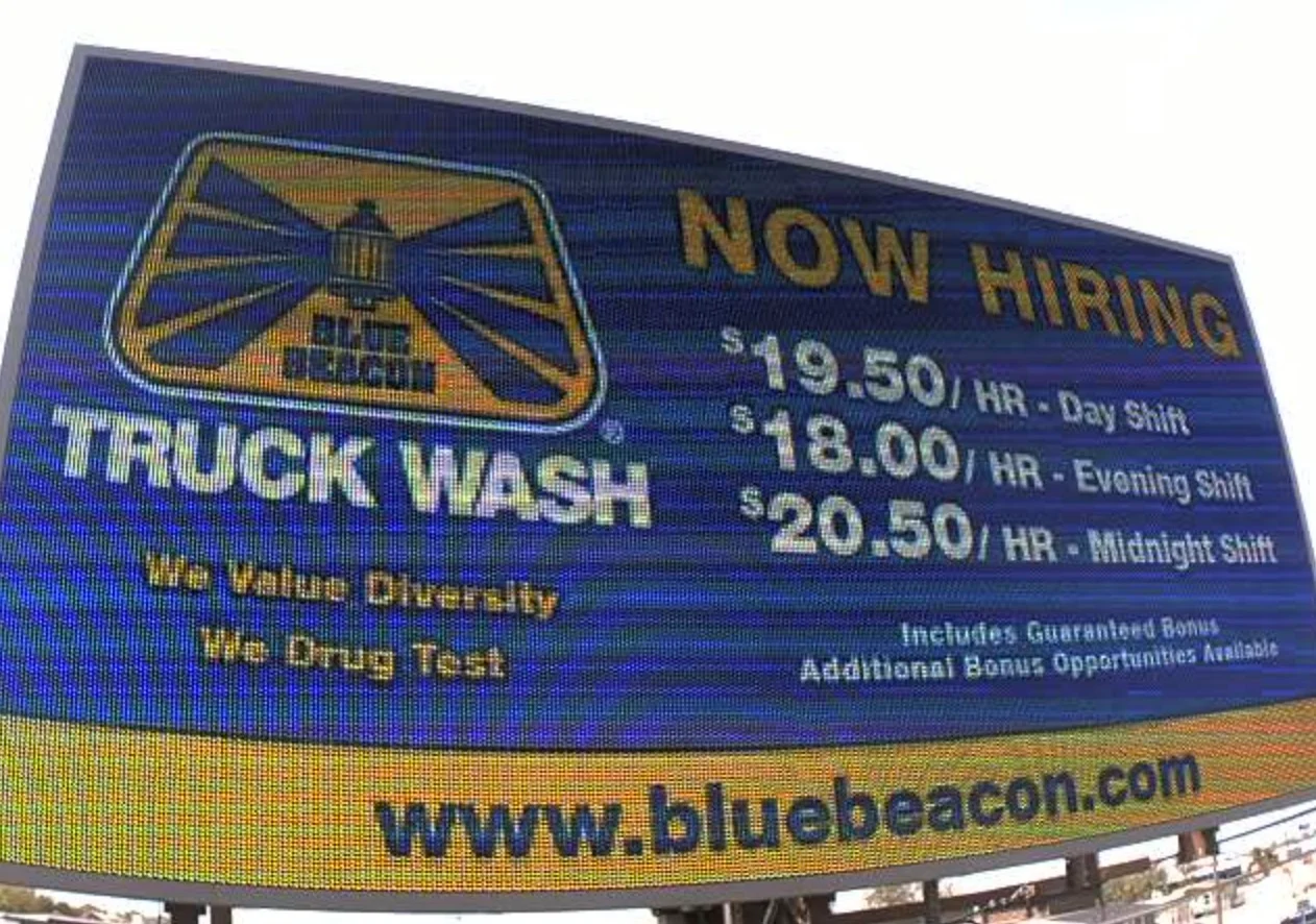 LED billboard advertising that they are hiring at Blue Beacon Truck Wash with the pay for the different shifts in blue and yellow 