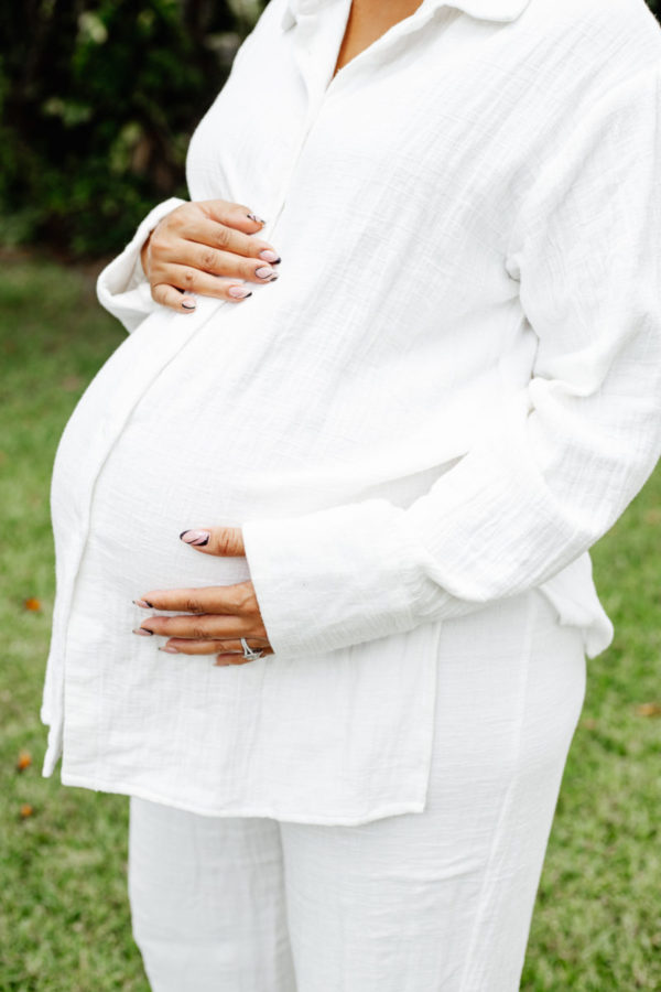 pregnant woman holding her belly dressed in white