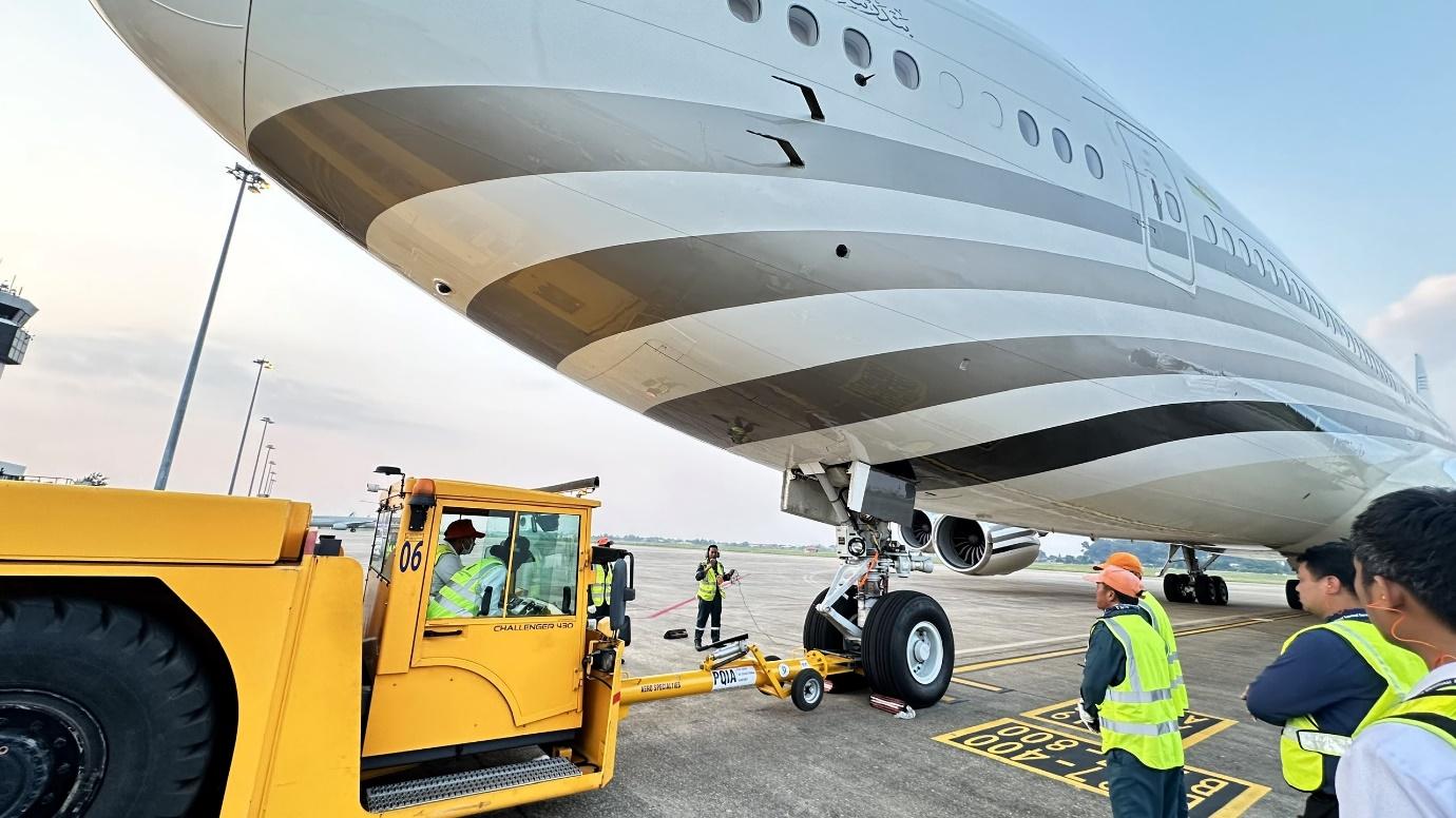 A plane being towed by a forkliftDescription automatically generated