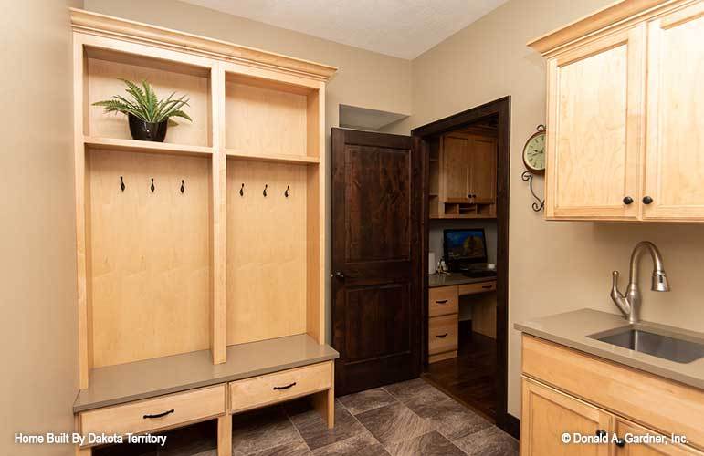 Laundry room with white appliances, wooden cabinetry, and a utility sink.