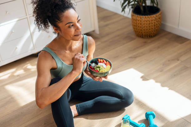 Fit woman enjoying a nutritious post-workout meal while following guidance from her virtual health coach.