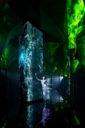 A person dancing in a room with a large fountain

Description automatically generated
