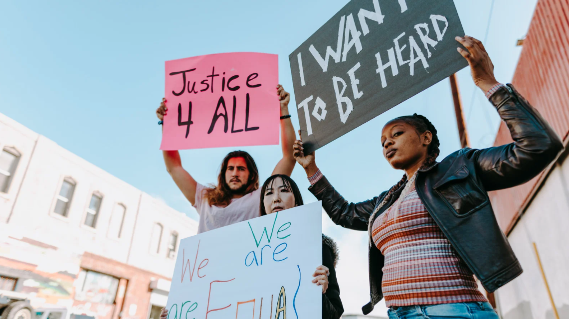 (Diverse group of peaceful protesters holding signs demanding justice and equality, highlighting a collective call for civil rights and social change.)