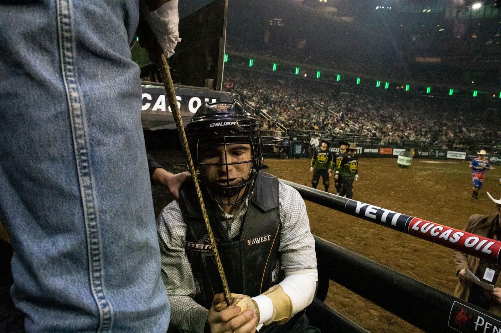 Rider in helmet holding a rope prepares to enter the arena.