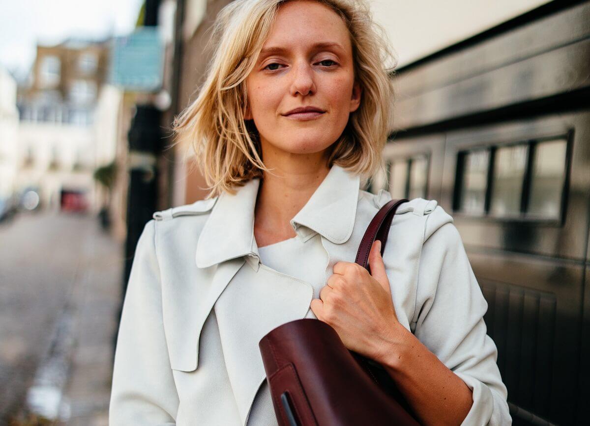 Jessica Kruger, founder of LUXTRA, wearing handbag, street in background