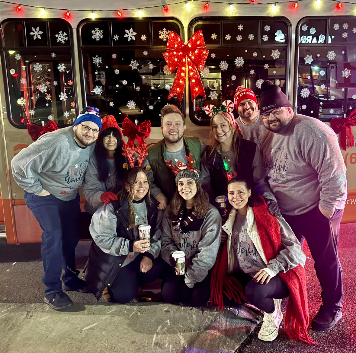 This Village Walk staff team outside on a snowy day in front of a Village Walk transportation bus