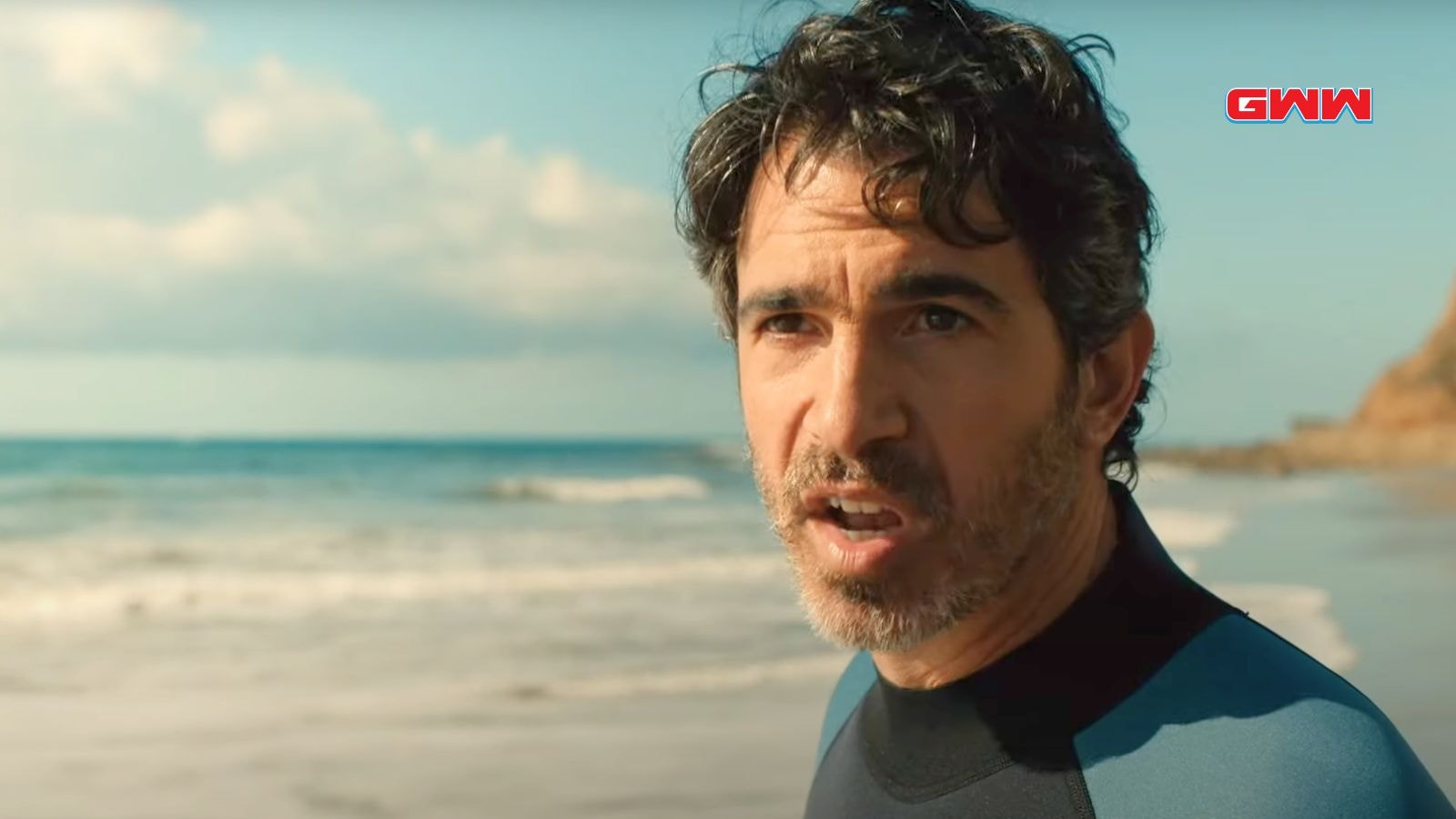 Nathan Bartlett speaking intently on a beach with waves in background.