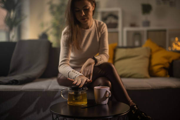 A person with a warm cup of herbal tea, unwinding as part of a bedtime detox routine.