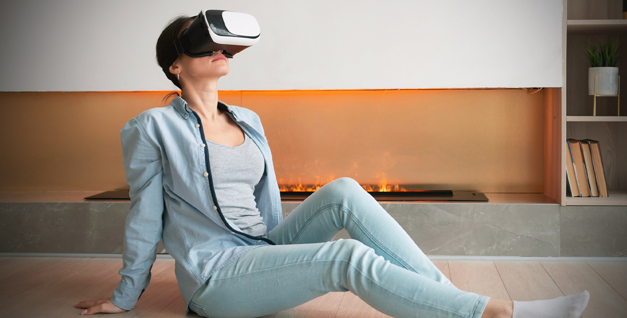 A woman seated on the floor, immersed in a virtual reality experience with a headset on