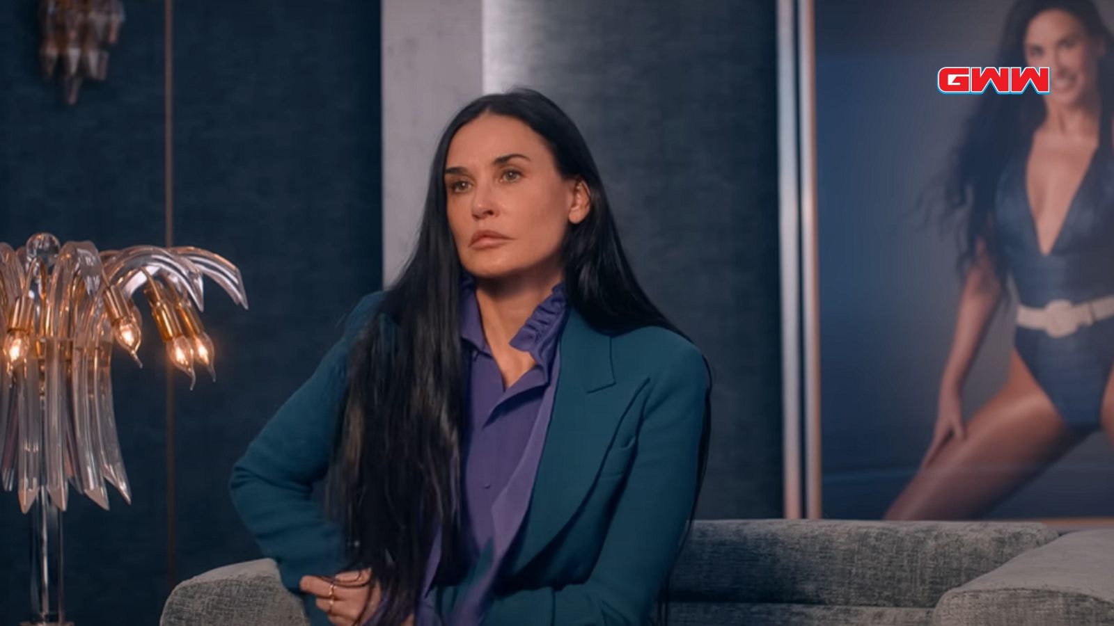 Demi Moore as Elisabeth Sparkle sitting on a couch, deep in thought