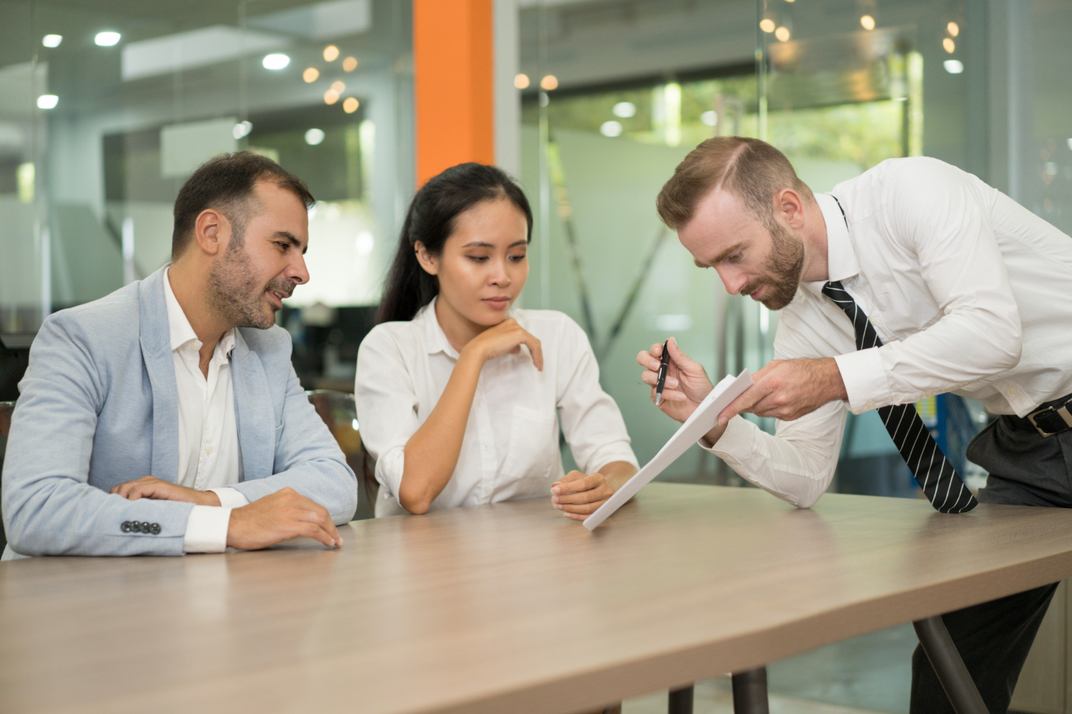 A consultant presents a detailed risk assessment report to two business managers in a meeting room.