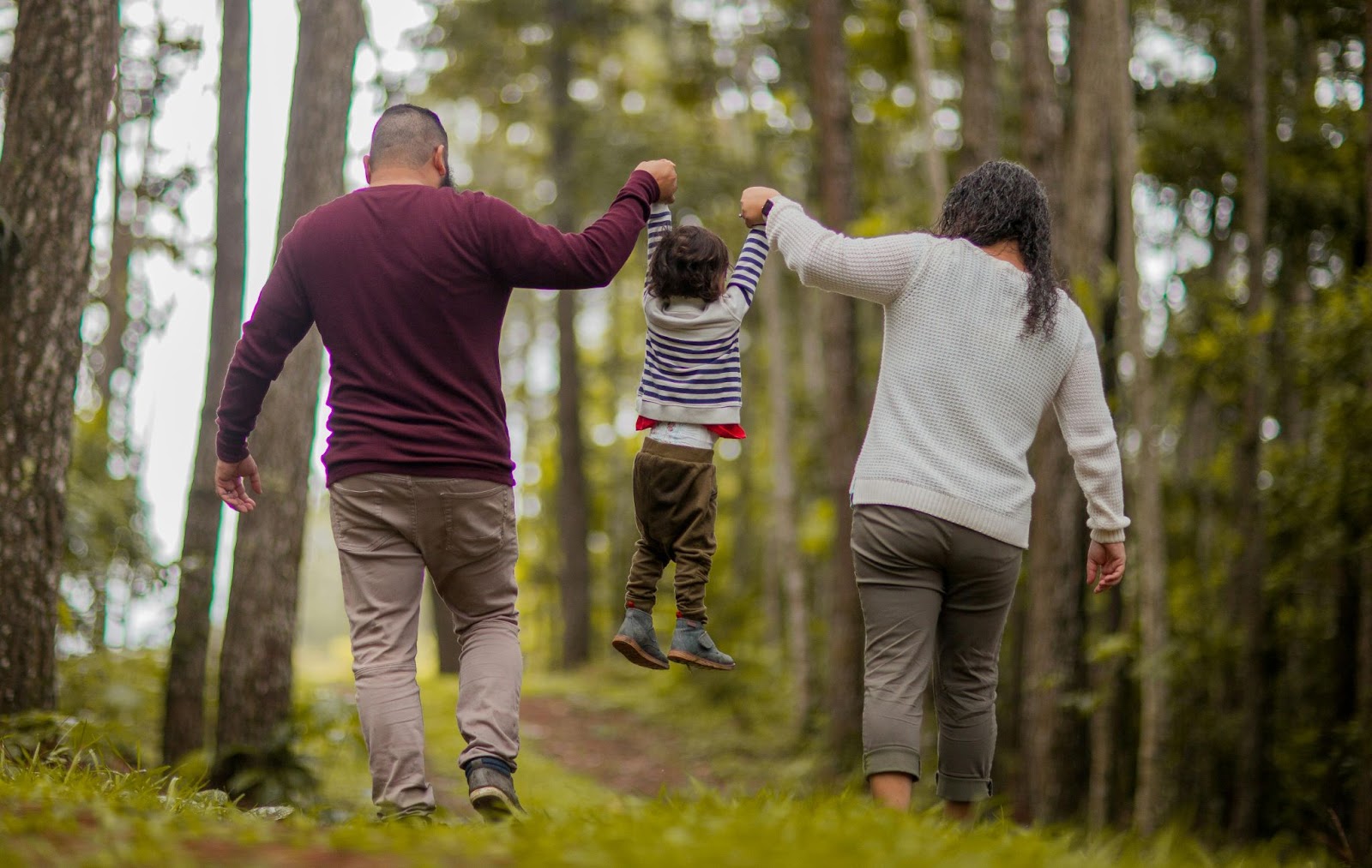 Two parents walking their young child in the woods