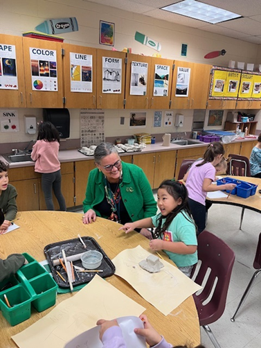 Dr. Reid speaking with a student working with clay at Poplar Tree Elementary School. 