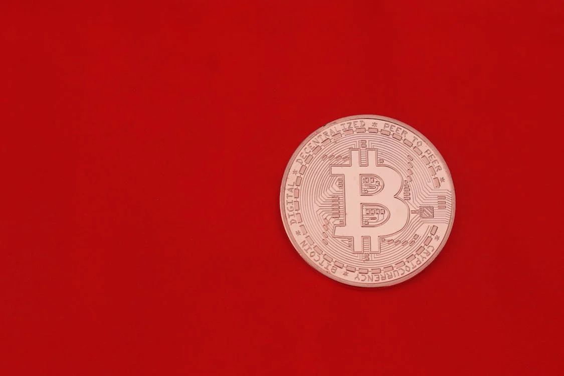 Single Bitcoin coin with a red background symbolizing cryptocurrency volatility and market trends